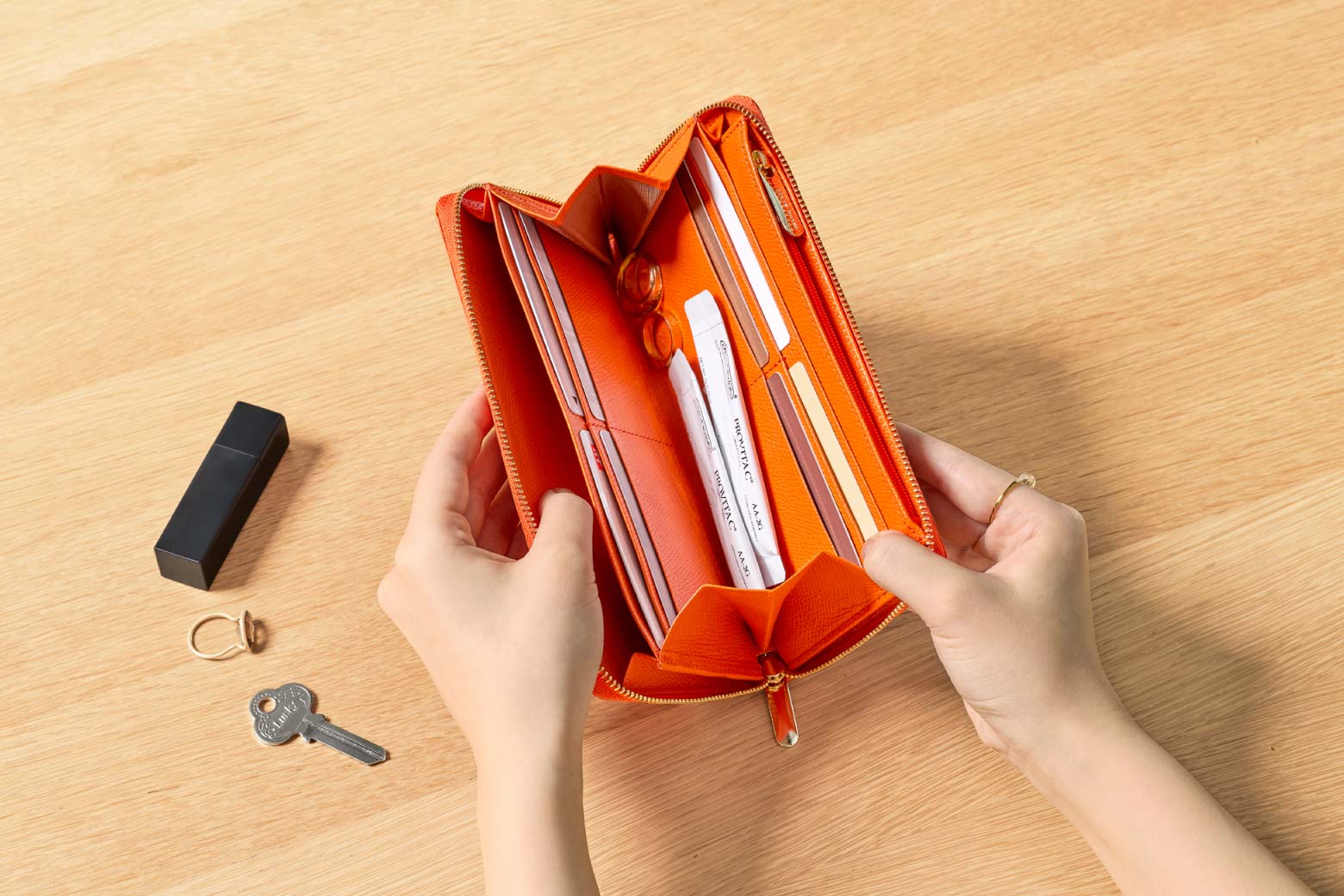 伊東屋　カラーチャート　ジップウォレットロングの中にサプリやアクセサリーなどの小物を収めている様子